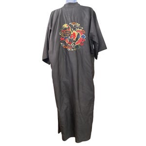 May include: A dark gray kimono-style robe with a vibrant embroidered dragon design on the back. The dragon is depicted in red, yellow, and blue, surrounded by swirling clouds. The robe has a long, flowing silhouette.
