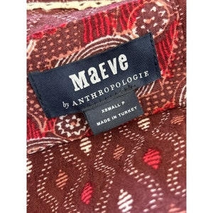 Puede incluir: Una etiqueta en blanco y negro con el texto "Maeve by Anthropologie" y "XSmall P Made in Turkey" sobre una tela estampada en rojo, blanco y marr&oacute;n.