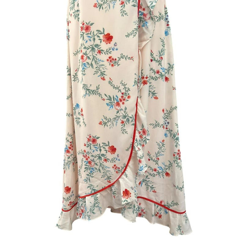 May include: A white wrap dress with a floral print and red trim. The dress has a ruffled hem and a tie at the waist.