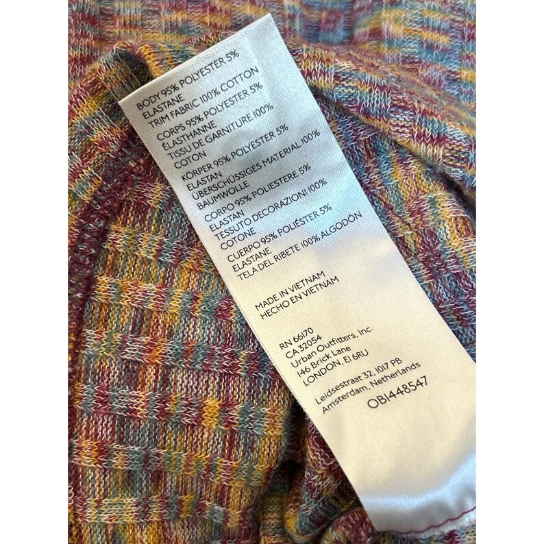 May include: A close-up of a clothing tag with a colorful, abstract pattern. The tag lists the fabric composition, care instructions, and the brand name "Urban Outfitters".
