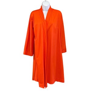 May include: Bright orange robe with long sleeves and a shawl collar. The robe is displayed on a white mannequin and has a relaxed fit. The fabric appears to be a smooth, lightweight material. The robe has a single pocket on the right side.