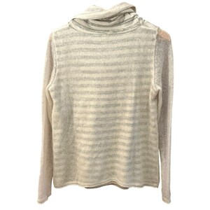 May include: A light-colored sweater with a cowl neck and long sleeves. The sweater features horizontal stripes in shades of gray and cream. The fabric appears to be a lightweight knit, suitable for layering. The sweater is displayed on a hanger.