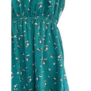 May include: A teal blue dress with a white floral pattern. The dress has a fitted bodice and a flowing skirt.