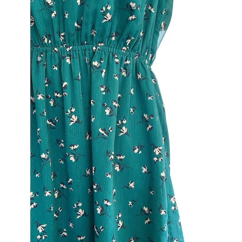 May include: A teal blue dress with a white floral pattern. The dress has a fitted bodice and a flowing skirt.