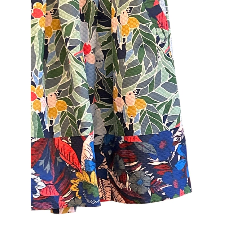 Puede incluir: Una falda azul y verde con estampado tropical de p&aacute;jaros y hojas. La parte inferior de la falda tiene un estampado floral rojo, azul y amarillo.