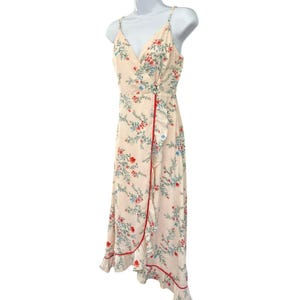 May include: A white midi dress with a floral print and a red and white trim. The dress has a V-neckline and a wrap style.
