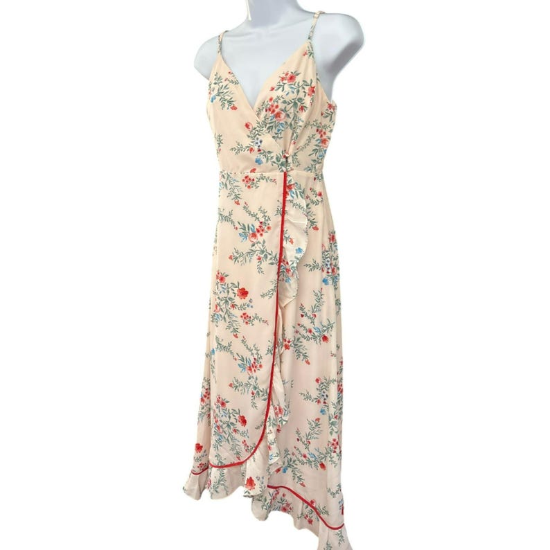 May include: A white midi dress with a floral print and a red and white trim. The dress has a V-neckline and a wrap style.