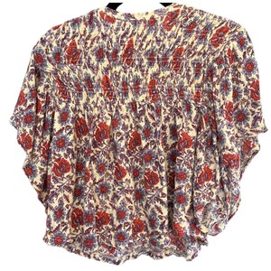 Peut inclure: Un haut &agrave; imprim&eacute; floral blanc, rouge et bleu avec un col pliss&eacute; et des manches courtes.