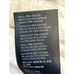 May include: A black fabric tag with white text detailing the material composition of a garment. The tag lists percentages of viscose, nylon, and elastane, along with the lining material. The tag also includes the text "MADE IN CHINA".