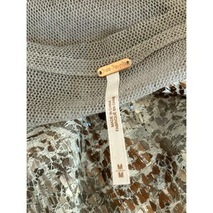 May include: A Free People brand, sequined, lace, and tulle dress with a brown and white pattern. The dress has a size tag that says "M" and "Made in China/Fabriqu&eacute; en Chine".