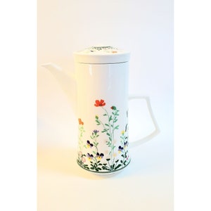 May include: White ceramic coffee pot with a floral design featuring red, yellow, blue, and green flowers. The pot has a lid and a handle.