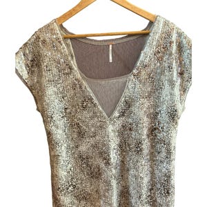 May include: A beige and silver sequined top with a V-neck and short sleeves. The top has a sheer, brown under layer.