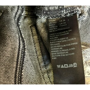 May include: A black and white care label with instructions for washing and drying a garment. The label includes the text "Colors, Use Only Bleach, Tumble Dry, Low Iron, May Be Dry Cleaned, Laver a la Machine a l'eau Froide avec Couleurs Similaires, Utiliser un Agent de Blanchiment sans Chlore si Necessarie, Secher par Culbutage a Basse Temperature, Repasser, au Besoin, a Tres Basse Temperature, Peut-etre etre Nettoye a Sec".