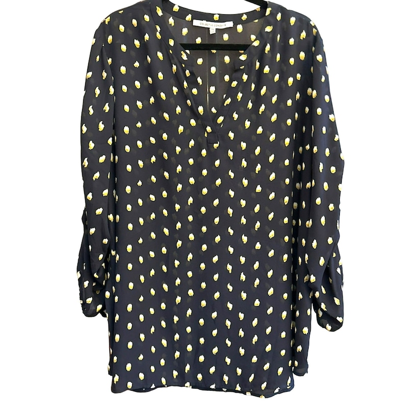 May include: A navy blue long-sleeved blouse with a white polka dot pattern. The blouse has a v-neck and a relaxed fit.