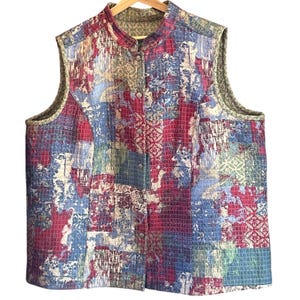 May include: A quilted vest with a colorful patchwork design. The vest features a mandarin collar and a button-up front. The color palette includes shades of red, blue, green, and beige. The vest is sleeveless and appears to be made of a soft, textured fabric.