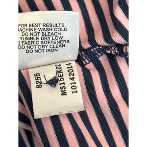 May include: Close-up of a garment tag with care instructions and product information. The tag reads "FOR BEST RESULTS MACHINE WASH COLD DO NOT BLEACH TUMBLE DRY LOW FABRIC SOFTENERS DO NOT DRY CLEAN DO NOT IRON." The garment has pink and navy blue stripes.