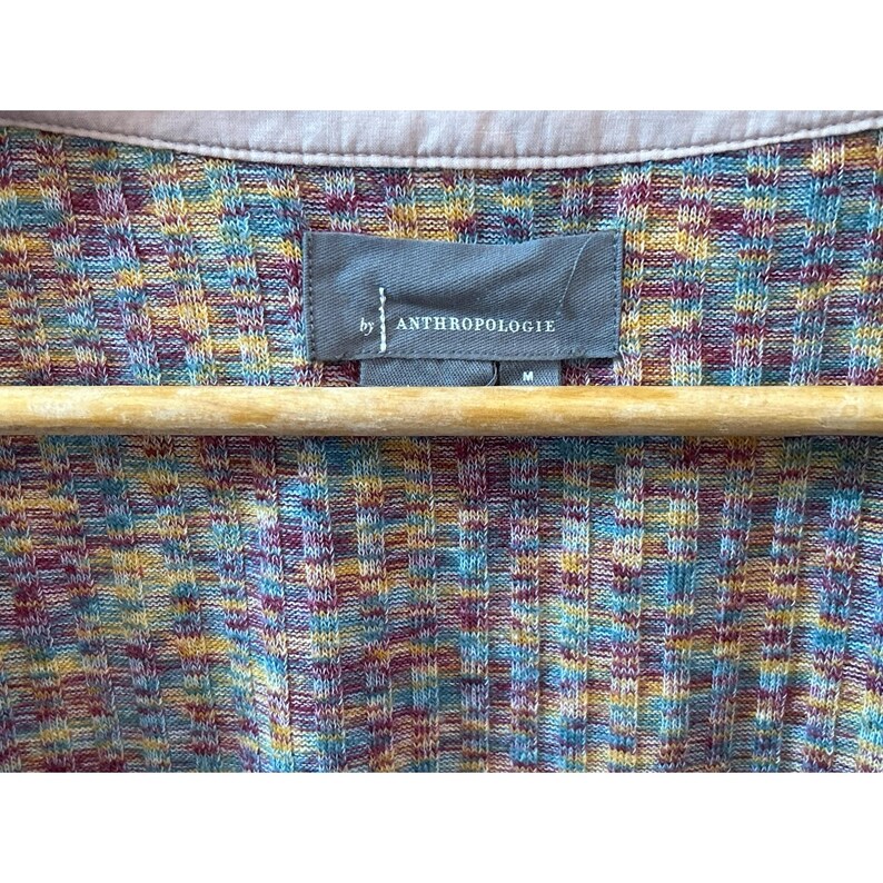 May include: A multi-colored striped cardigan with a gray tag that reads "by Anthropologie" and a size "M".