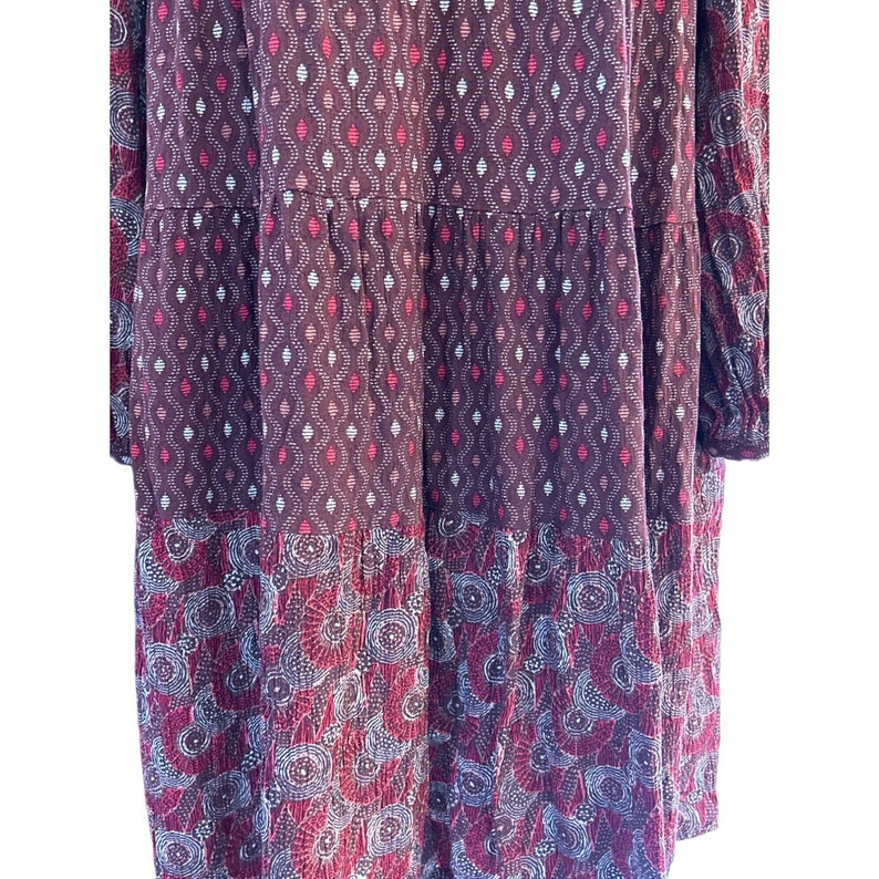 Puede incluir: Un vestido de manga larga con un dise&ntilde;o de capas. El vestido est&aacute; hecho de una tela suave y ligera y presenta un patr&oacute;n geom&eacute;trico en tonos de rosa, blanco y marr&oacute;n.