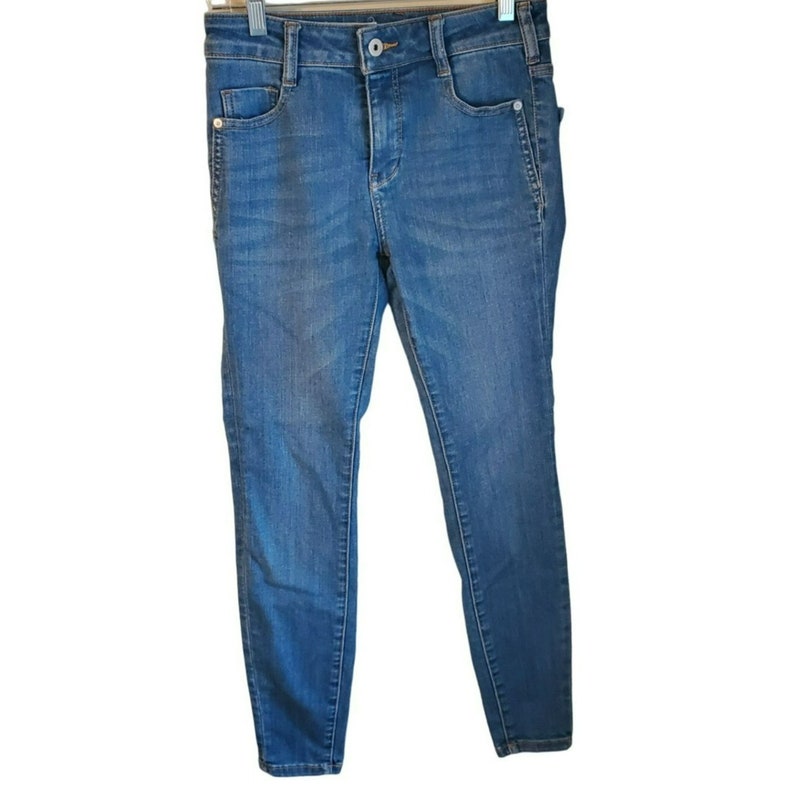May include: A pair of blue denim jeans with a slim fit. The jeans have a classic five-pocket style and a zipper fly.