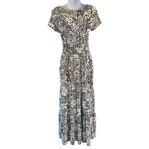 May include: A floor-length dress with a black and white floral and geometric pattern. The dress has short sleeves and a scoop neckline. The skirt has a tiered design. The dress is displayed on a mannequin.
