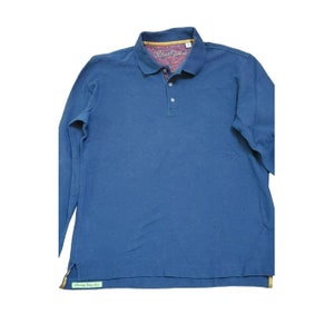 May include: A long-sleeved blue polo shirt with a button-up collar. The shirt has a small logo on the left side of the chest that reads "Robert Graham". The shirt also has a small green tag on the bottom left side that reads "Family Matters".