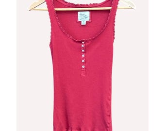 May include: A red tank top with a scoop neck and a row of white buttons down the front. The top has a scalloped trim along the neckline and armholes. The tag reads "Love Tea Lounge".