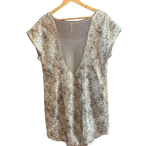 May include: A sleeveless, silver and brown patterned dress with a deep V-neck and a sheer back panel.