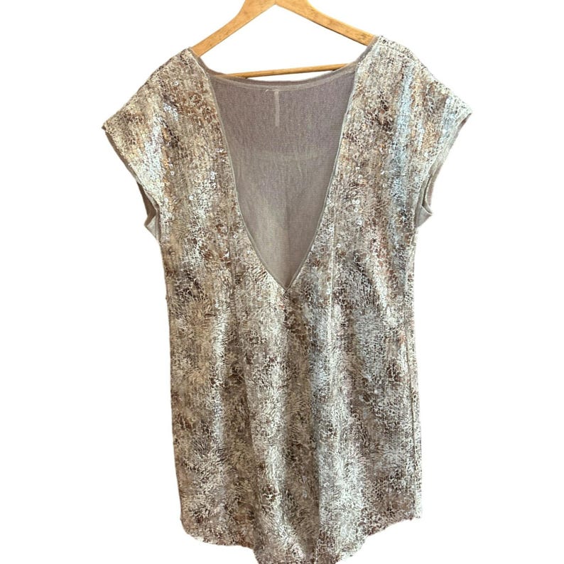 May include: A sleeveless, silver and brown patterned dress with a deep V-neck and a sheer back panel.