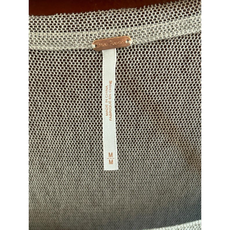 May include: A white mesh top with a Free People tag. The tag says "Made in China" and "Fabriqu&eacute; en Chine". The size tag says "M".