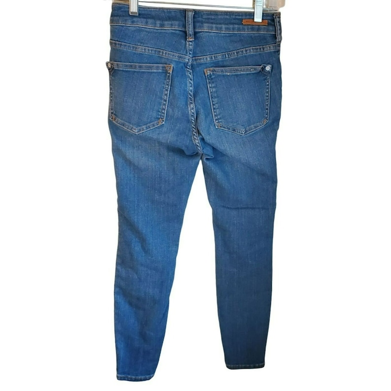 May include: A pair of blue denim jeans with a slim fit. The jeans have a button fly and belt loops.