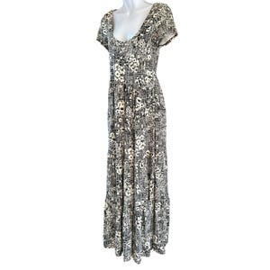 May include: A floor-length dress with a scoop neckline and short sleeves. The dress features a black and white floral and geometric pattern. The dress is displayed on a mannequin.