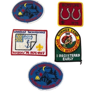 Puede incluir: Colección de parches bordados vintage. Los diseños incluyen un parche rojo y amarillo "BOYS LIFE" con herraduras, un parche verde "SUMMER CAMP" y un parche azul con una tienda de campaña y una fogata. Otros parches presentan texto.
