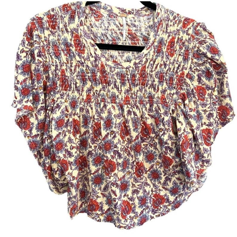 Peut inclure: Un chemisier &agrave; manches courtes &agrave; imprim&eacute; floral blanc, rouge et bleu avec une taille &eacute;lastique fronc&eacute;e.