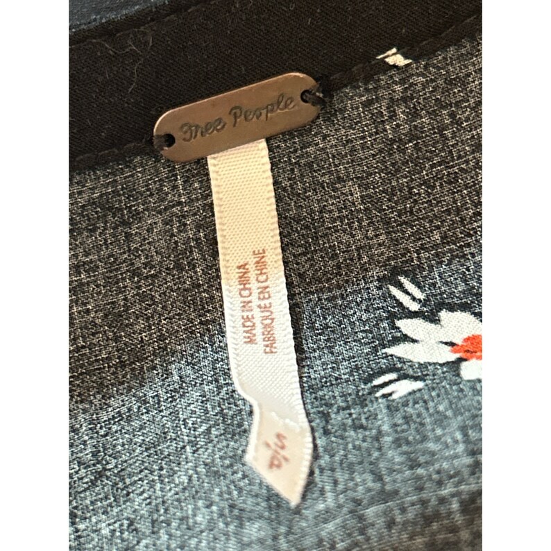 Może przedstawiać: Czarno-biała tkanina w kwiatowy wz&oacute;r z metką Free People z napisem "Made in China, Fabrique en Chine".