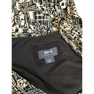 May include: A black and cream-colored dress with a geometric and floral pattern. The dress features a black lining and a label that reads "Maeve by Anthropologie" and "Small Made in China."
