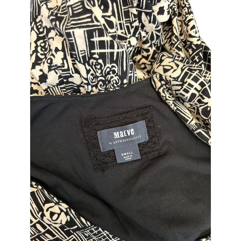 May include: A black and cream-colored dress with a geometric and floral pattern. The dress features a black lining and a label that reads "Maeve by Anthropologie" and "Small Made in China."
