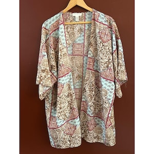 May include: A light blue and brown patterned kimono with a paisley design. The kimono has a V-neck and 3/4 sleeves.