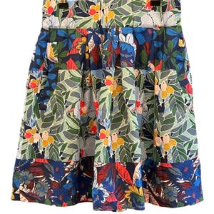 Puede incluir: Una falda de estampado floral azul, verde, rojo y amarillo con dise&ntilde;o plisado. La falda tiene un patr&oacute;n de patchwork con diferentes dise&ntilde;os florales.