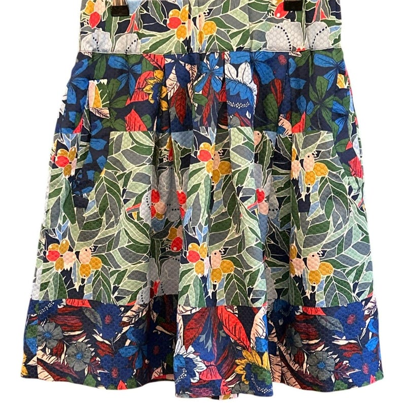 Puede incluir: Una falda de estampado floral azul, verde, rojo y amarillo con dise&ntilde;o plisado. La falda tiene un patr&oacute;n de patchwork con diferentes dise&ntilde;os florales.
