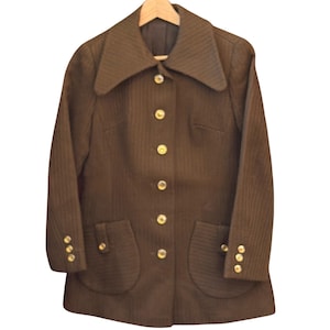 May include: A dark brown jacket featuring a textured vertical stripe pattern, a wide collar, and a front button closure. The garment includes two front patch pockets and three gold-toned buttons on each sleeve cuff, all accented with gold-toned buttons.