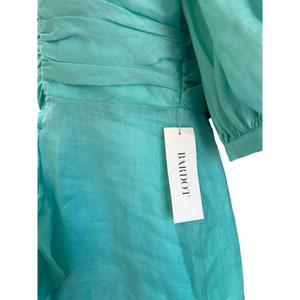 May include: A turquoise blue dress with a ruffled hem and a tag that reads "BARDOT".