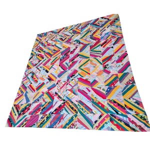 May include: A large, colorful quilt with a patchwork design. The quilt features a variety of fabrics in shades of pink, blue, yellow, green, and red. The pattern is made up of diagonal stripes and geometric shapes, creating a vibrant and eye-catching textile.