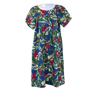 Peut inclure: Robe bleue ornée d'un motif floral tropical avec des fleurs rouges et des feuilles vertes. La robe a des manches courtes et un col rond. Le tissu semble être léger, adapté aux climats chauds.