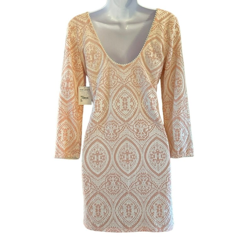 Puede incluir: Un vestido de color melocot&oacute;n con un patr&oacute;n de encaje blanco. El vestido tiene un escote redondo y mangas largas.