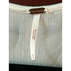 May include: White Free People brand clothing tag with the text "Made in India Fabrique en Inde" and "XS TP" printed on it.