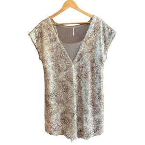 May include: A silver sequined top with a V-neck and short sleeves. The top is layered over a brown tank top.