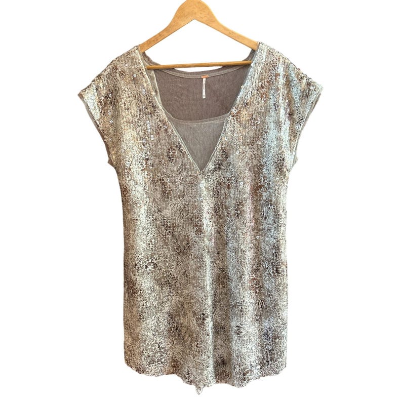 May include: A silver sequined top with a V-neck and short sleeves. The top is layered over a brown tank top.
