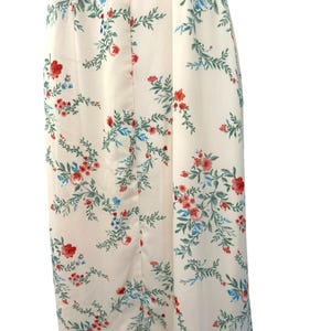 May include: A white maxi dress with a floral print featuring red and blue flowers. The dress has a button-up front and a fitted bodice.