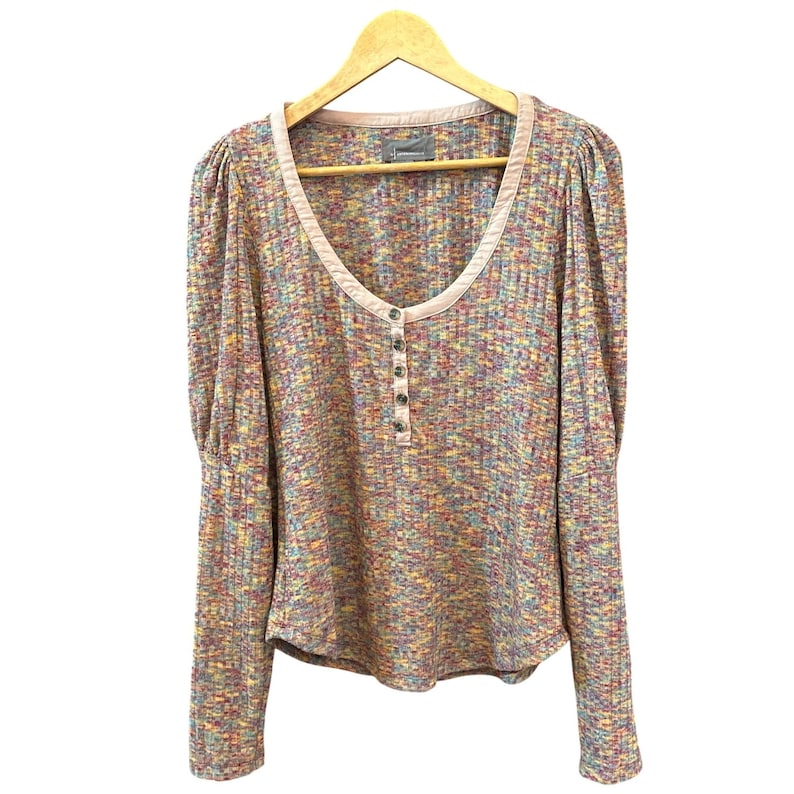 May include: A long-sleeved, multi-colored, button-up shirt with a scoop neck and a pink trim. The shirt has a speckled pattern with shades of pink, blue, yellow, and green.