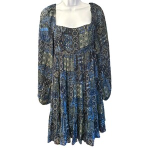 May include: A blue and green patterned mini dress with long sleeves and a square neckline. The dress has a tiered skirt and a relaxed fit.